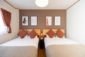 2 letti in una camera con immagini a parete di Maison Raffine ad Osaka