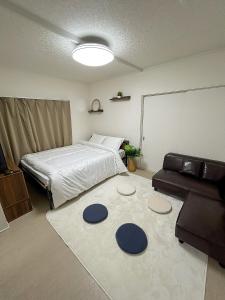 a bedroom with a bed and a couch and a rug at COMMA House in Yokohama