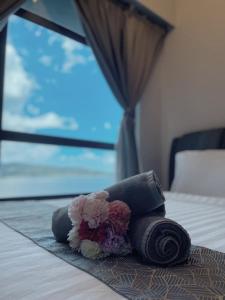 a pile of towels and flowers on a bed at Jesselton Quay Kota Kinabalu City Centre by LW Suites in Kota Kinabalu
