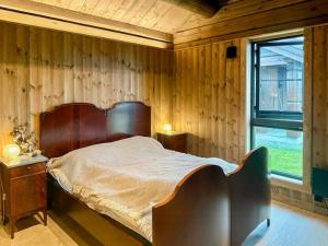 a bedroom with a wooden wall with a bed and a window at Modern Family Cabin Near Kikut In Geilo in Flatåker