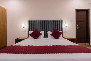 a bedroom with a large bed with red pillows at Novara Hotel Madhapur in Hyderabad