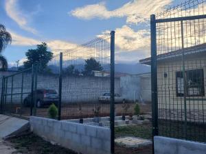a fence in front of a house with a car at Casa familiar in El Molino