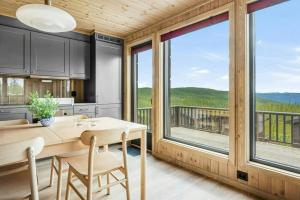 een keuken en eetkamer met een tafel en stoelen en grote ramen bij Mountain Cabin With Panoramic Views In Norefjell in Runn