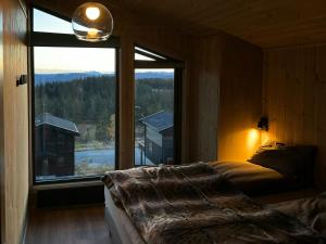 een slaapkamer met een bed en een groot raam bij Mountain Cabin With Panoramic Views In Norefjell in Runn