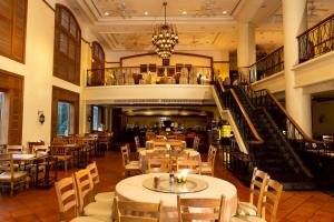 a restaurant with tables and chairs and a staircase at CS Pattani Hotel in Ban Ru Sa Mi Lae