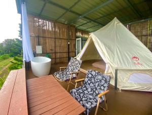 a tent with two chairs and a table and a bench at หรรษาวิว ที่พักเขาค้อ เพชรบูรณ์ in Khao Kho
