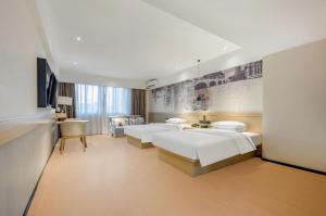 a large bedroom with two beds and a desk at City Comfort Inn Nanning Xingning District Government Maternal and Child Health Hospital in Nanning