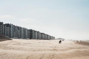 a beach with buildings and people walking on it at C-Hotels Excelsior in Middelkerke