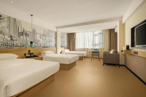 a hotel room with two beds and a television at City Comfort Inn Wuzhou High-speed Railway Station Canghai Lake Park in Wuzhou +194 photos