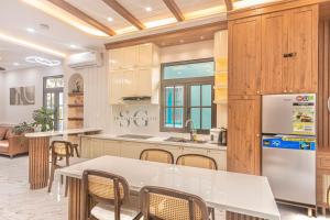 une cuisine avec une table, des chaises et un réfrigérateur dans l'établissement Novaworld Phan Thiết -Villa Nghỉ dưỡng, à Bình Tú