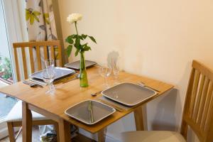 uma mesa de madeira com óculos e um vaso com uma flor em Plover Cottage em Huddersfield