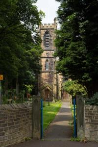 an old stone church with a fence and a sidewalk at Plover Cottage in Huddersfield