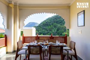 une salle à manger avec une table et des chaises devant une fenêtre dans l'établissement StayVista at Samar Fateh Garh with Bonfire, Lawn, AC, à Rāma