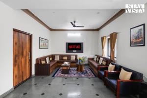 un salon avec des canapés et une télévision dans l'établissement StayVista at Samar Fateh Garh with Bonfire, Lawn, AC, à Rāma