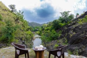 une table et deux chaises à côté d'une rivière dans l'établissement StayVista at Samar Fateh Garh with Bonfire, Lawn, AC, à Rāma
