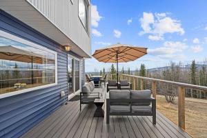 eine Terrasse mit Stühlen und einem Regenschirm auf einem Haus in der Unterkunft Scandi Aurora Villa - Private Sauna & Epic Views in Chena River Seaplane Base