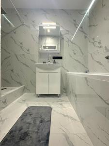 a white bathroom with a sink and a mirror at Видові Апартаменти Residential GREAT ліфт, вода, тепло WiFi Працюють без світла in Kyiv