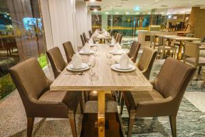 New Season Square Hotel - SHA Plus في هات ياي: طاولة خشبية طويلة مع كراسي في المطعم