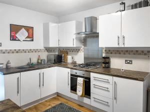 a kitchen with white cabinets and a stove top oven at Miner's Rest in Rowrah
