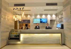 two people sitting at a counter in a lobby at City Comfort Inn Wuhan Optics Valley OuYada Yangjiawan Metro Station in Wuhan