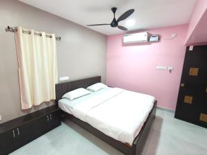 a bedroom with a bed and a pink wall at CHETTINAD HOMESTAy in Chidambaram
