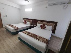 two beds in a room with white walls at Hotel D Palace in Faydābād