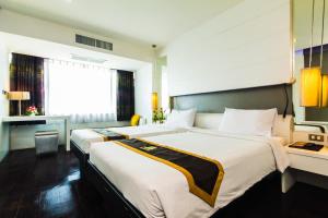 a hotel room with two beds and a window at Khon Kaen Hotel in Khon Kaen