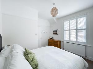 a white bedroom with a bed and a window at Pebble Hideaway - Uk50551 in Worthing +3 photos