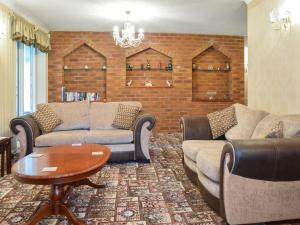 a living room with couches and a brick wall at Quail Cottage - Uk50659 in Little Singleton