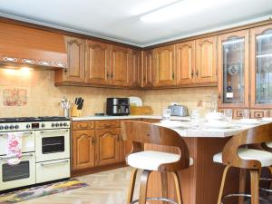 a kitchen with wooden cabinets and a island with bar stools at Quail Cottage - Uk50659 in Little Singleton +12 photos