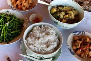 a table topped with bowls of rice and vegetables at Forest Floor Lodge in Cat Tien