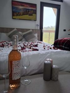 - une bouteille de vin et deux verres sur une table avec un lit dans l'établissement Aframe Lac Malei, à Petrila