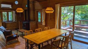 a dining room with a wooden table and chairs at 自然豊かな森の中に静かに佇むログハウス #貸別荘 #一棟貸切 #グループ旅行や家族旅行におすすめ #広々吹き抜けリビング #BBQのできるウッドデッキ #ジブリ風空間 #満天の星空 #鋸南 #南房総 #komorebi in Kyonan