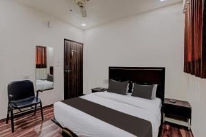 a bedroom with a large bed and a chair at Hotel O Royal Inn in Ahmedabad
