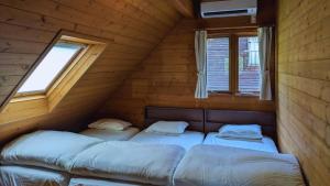 a room with three beds in a log cabin at 自然豊かな森の中に静かに佇むログハウス #貸別荘 #一棟貸切 #グループ旅行や家族旅行におすすめ #広々吹き抜けリビング #BBQのできるウッドデッキ #ジブリ風空間 #満天の星空 #鋸南 #南房総 #komorebi in Kyonan