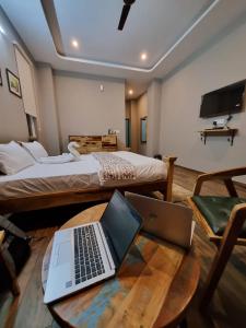 a room with a bed and a table with a laptop at Alchemy Bistro and Inn, Dharamshala in Dharmsala