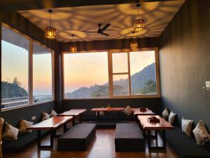 a restaurant with tables and benches and large windows at Alchemy Bistro and Inn, Dharamshala in Dharmsala
