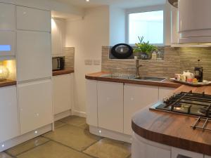 una cucina con mobili bianchi e un lavandino di Samphire Cottage a Brixham