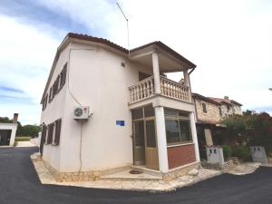 a white house with a balcony on a street at Comfortable holiday home only 500m to the sea with outdoor kitchen, wifi and airco in Banjole