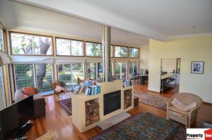 Una sala de estar con chimenea y muchas ventanas. en Tomorrow Jervis Bay - Waterfront with Swimming Pool, en Callala Bay