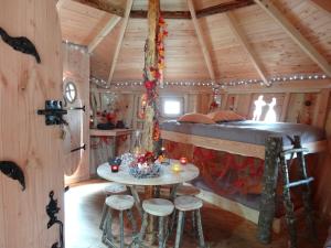 un lit dans une cabane dans les arbres avec une table et des tabourets dans l'établissement Les Cabanes De Pyrene, à Cazarilh