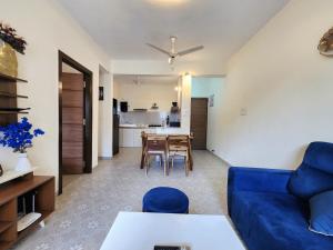 a living room with a blue couch and a table at Beachside 1BHK Apartment - Pool, Gym & Modern Comforts, Candolim in Candolim