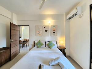 a bedroom with a large white bed and a table at Beachside 1BHK Apartment - Pool, Gym & Modern Comforts, Candolim in Candolim +38 photos