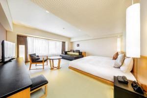 a hotel room with a large bed and a television at Resorpia Beppu in Beppu
