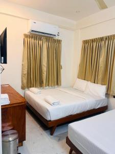 Un dormitorio con dos camas y una ventana. en Vallimony Luxury Stays, en Trivandrum