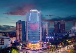 a city skyline with a tall building with lights at Kyriad Marvelous Hotel Xiangyin Bus Station in Xiangyin