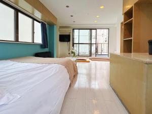 a bedroom with a bed and a kitchen with windows at Asakusa Sakura in Tokyo