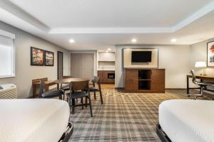 a hotel room with two beds and a table and a television at AmericInn by Wyndham Mounds View Minneapolis in Mounds View