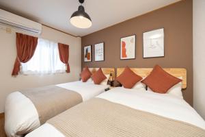 2 letti in una camera d'albergo con 2 letti sidx sidx di Maison Raffine ad Osaka