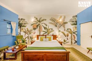 a bedroom with a bed with palm trees on the wall at StayVista at Villa Nimaya with Lawn & Pool in Saligao +31 photos